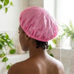 Femme aux tresses portant le bonnet de douche Comfort Fit rose dans une salle de bain