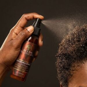 Main d'homme qui vaporise un spray hydratant sur des cheveux crépus courts